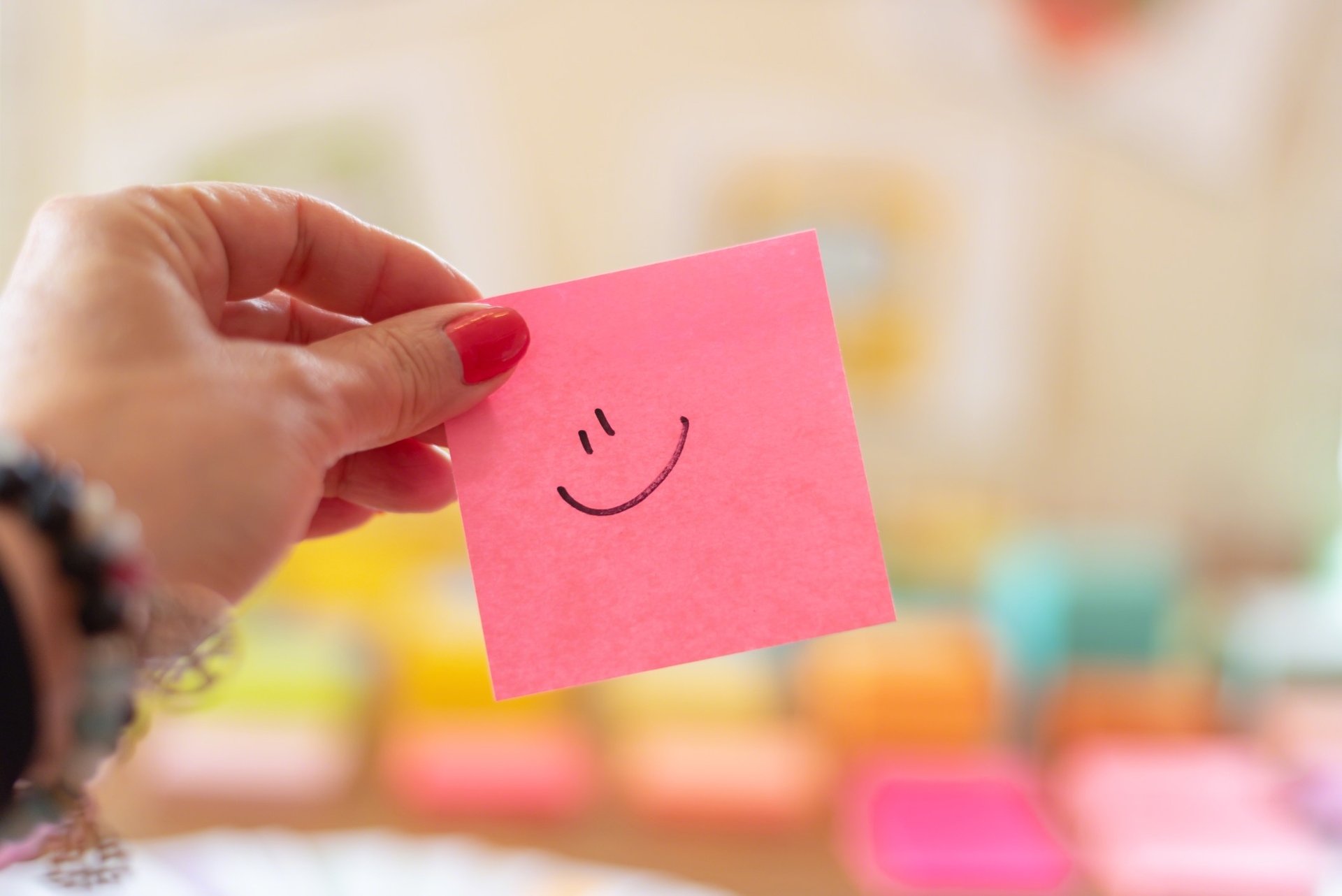 Bright pink sticky note with a smiley face
